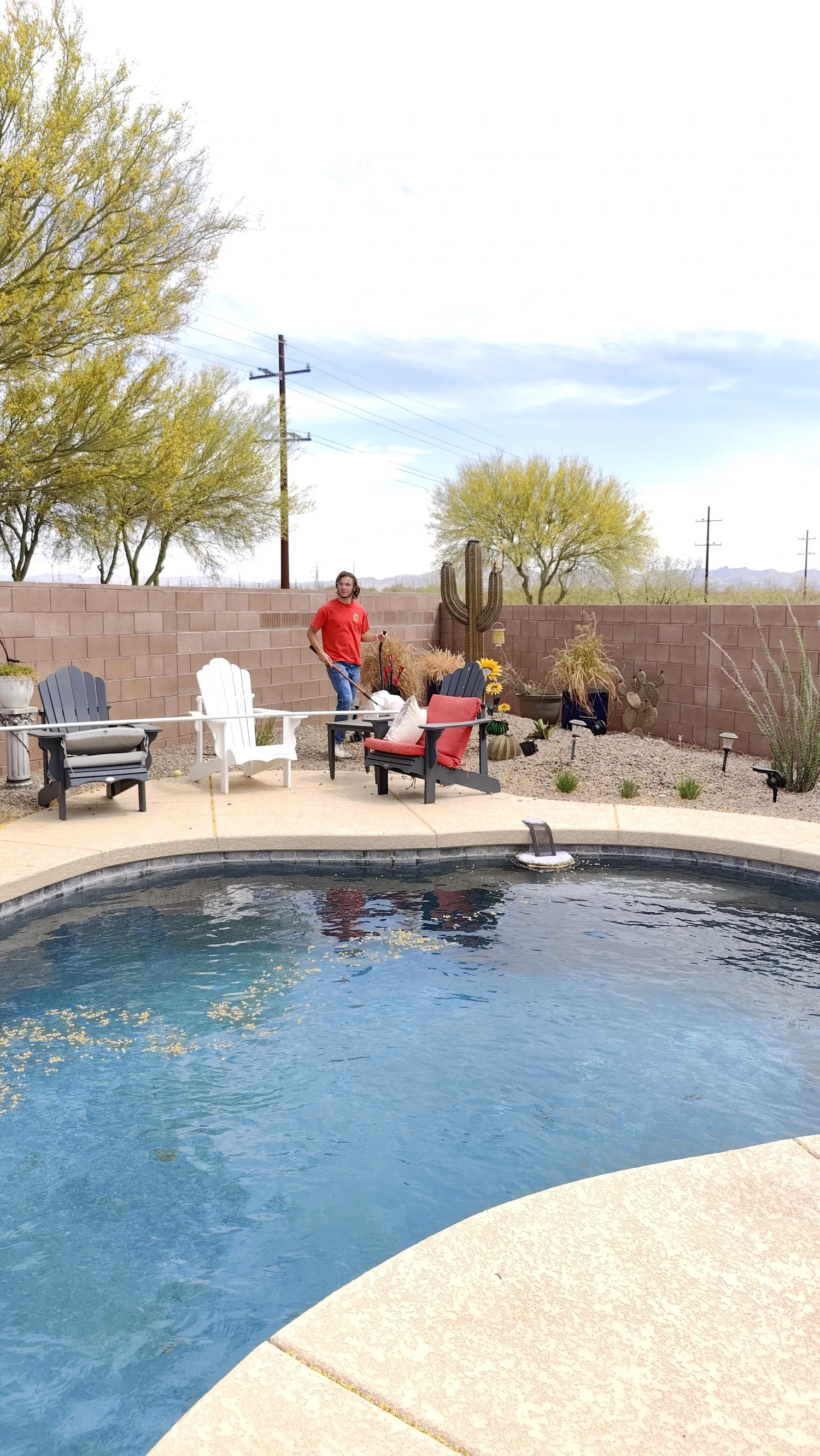 Scoop Doggy Logs team member scooping near a pool and desert landscaping